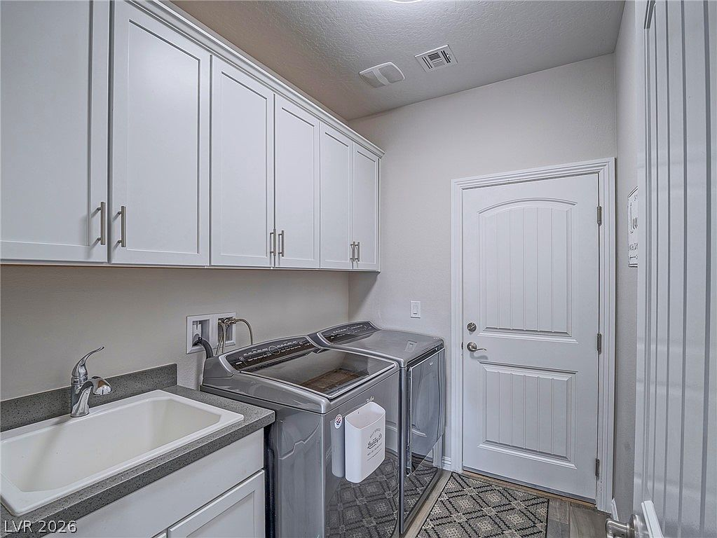 Laundry room with sink, cabinets, washer, and dryer