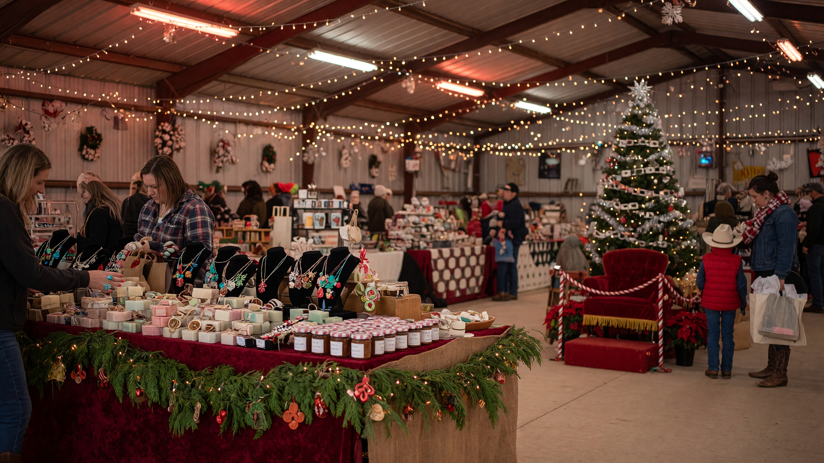 Holiday craft fair inside a decorated pavilion with vendor booths, string lights, and shoppers browsing handmade goods