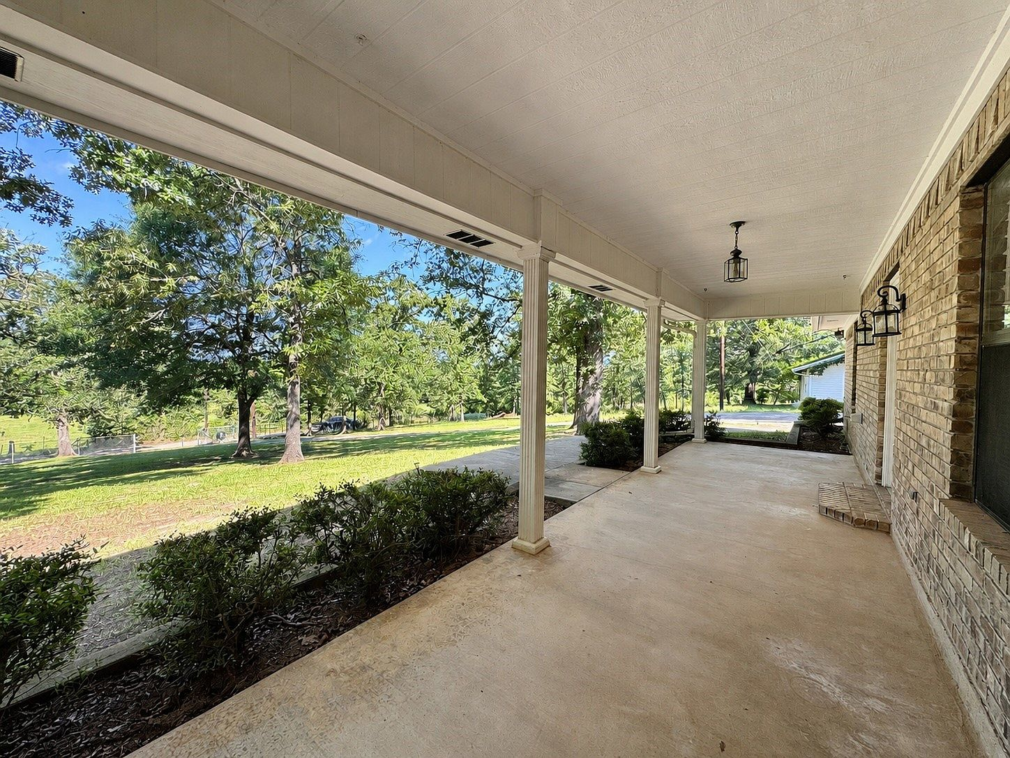 Covered front porch with white columns and cream brick