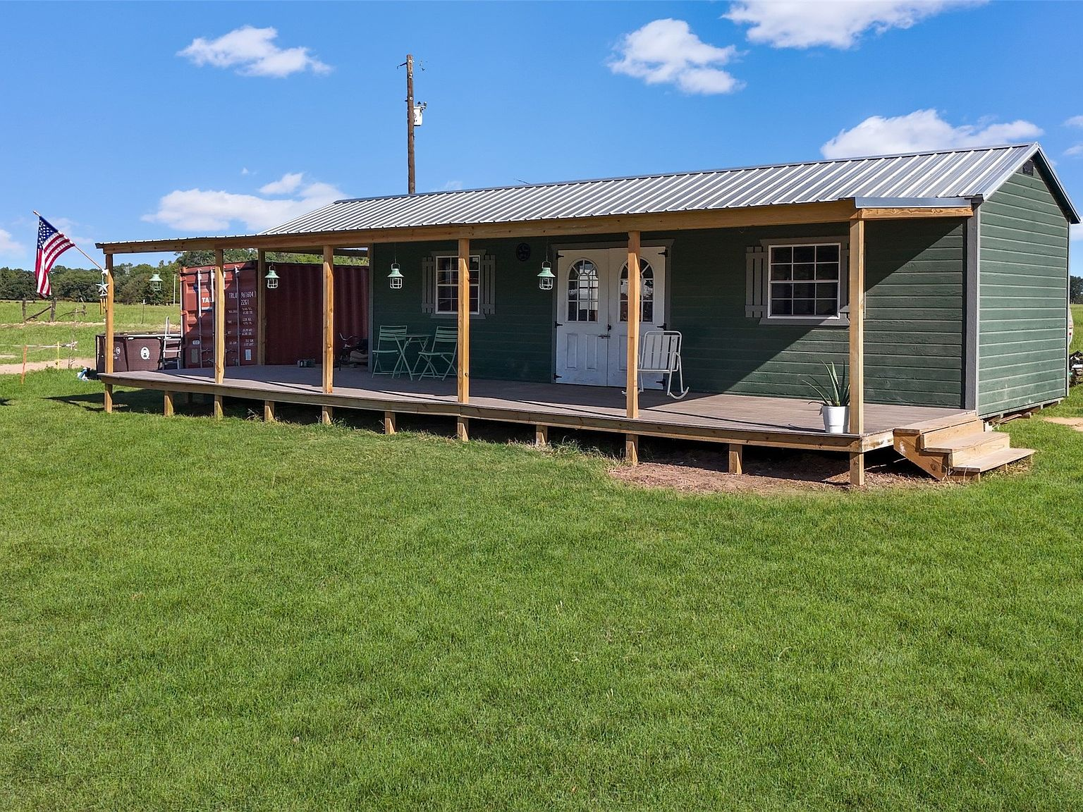 Green-sided tiny home with covered porch and wood posts