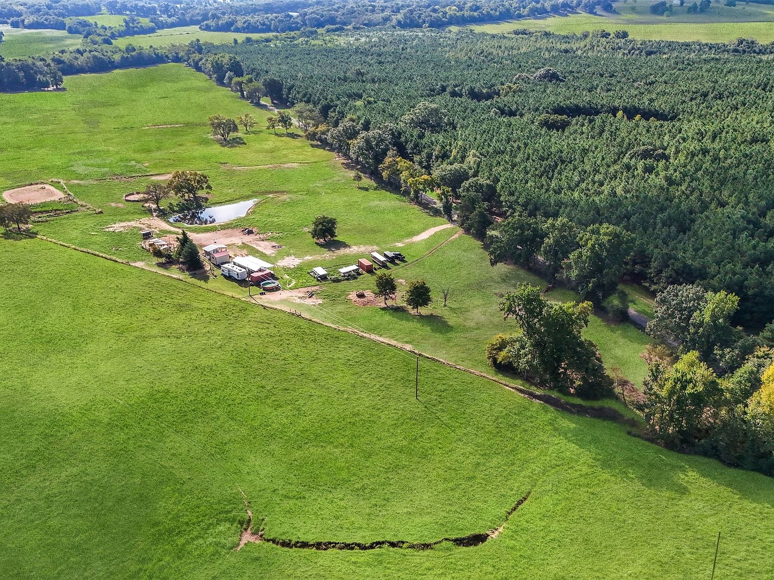 High-altitude drone view of entire property with wooded boundary