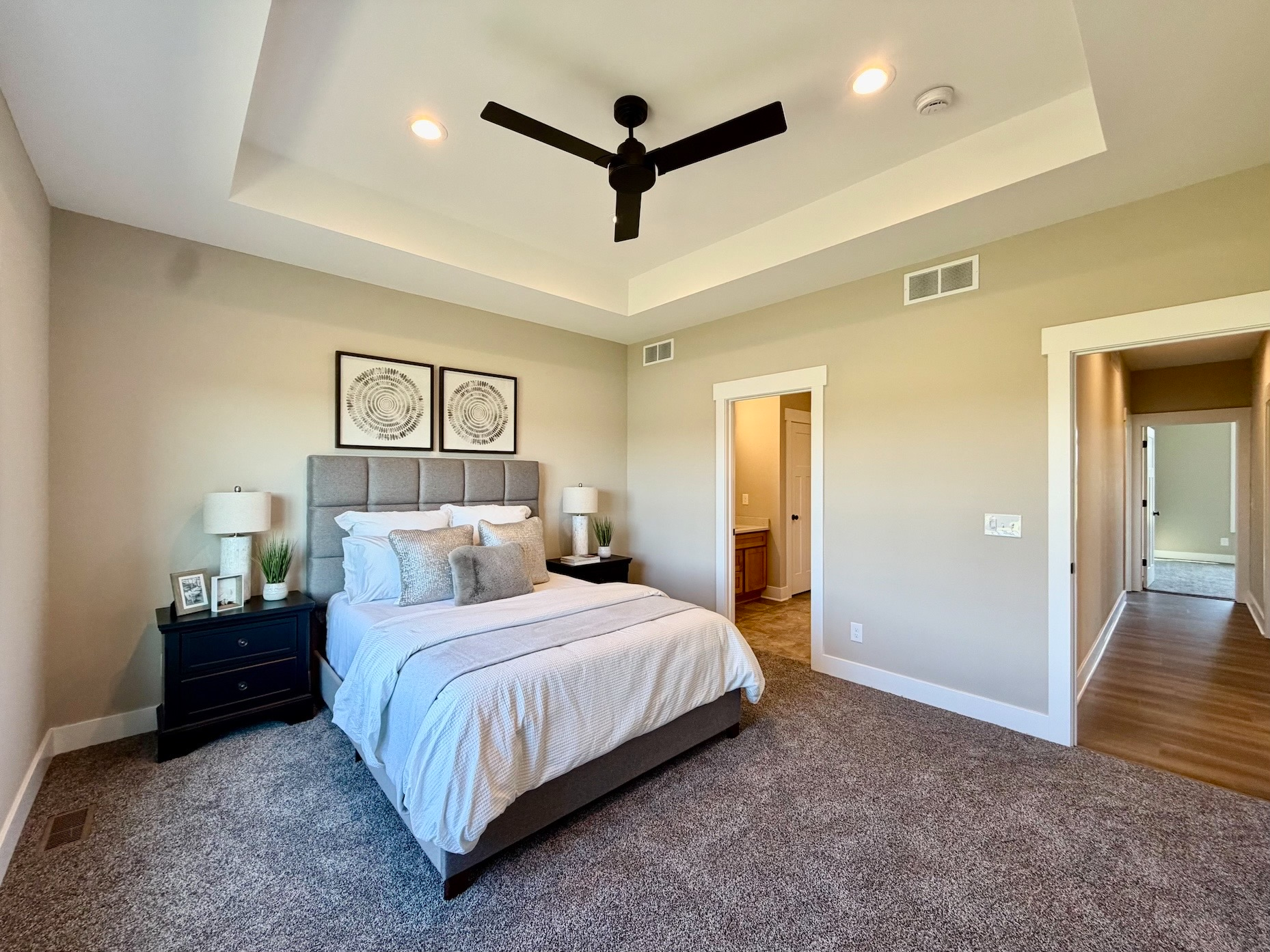 Furnished primary bedroom with tray ceiling, queen bed, and nightstands