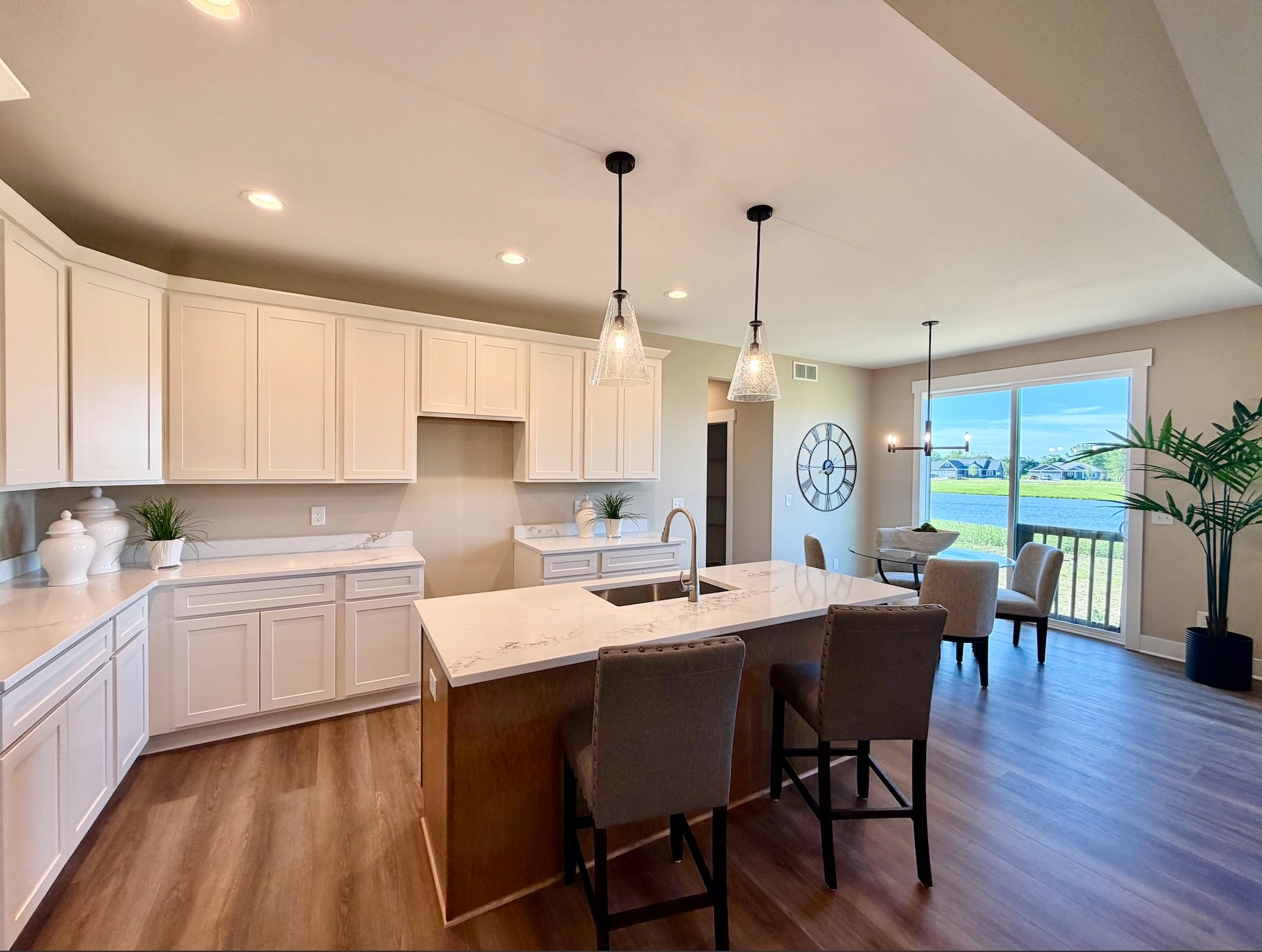 Staged gourmet kitchen with island seating, dining table, and quartz countertops