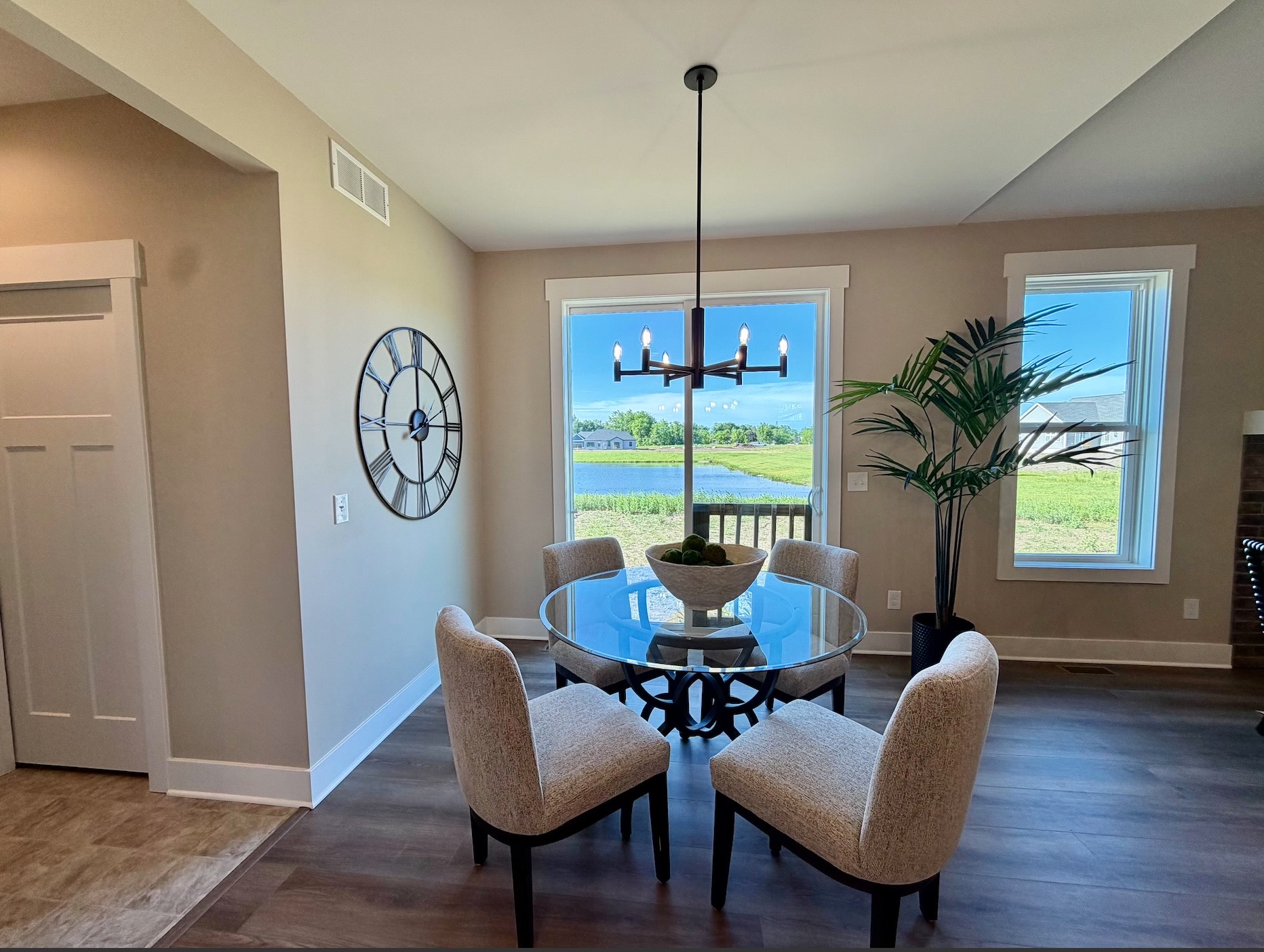 Staged dining area with glass-top table, upholstered chairs, and chandelier