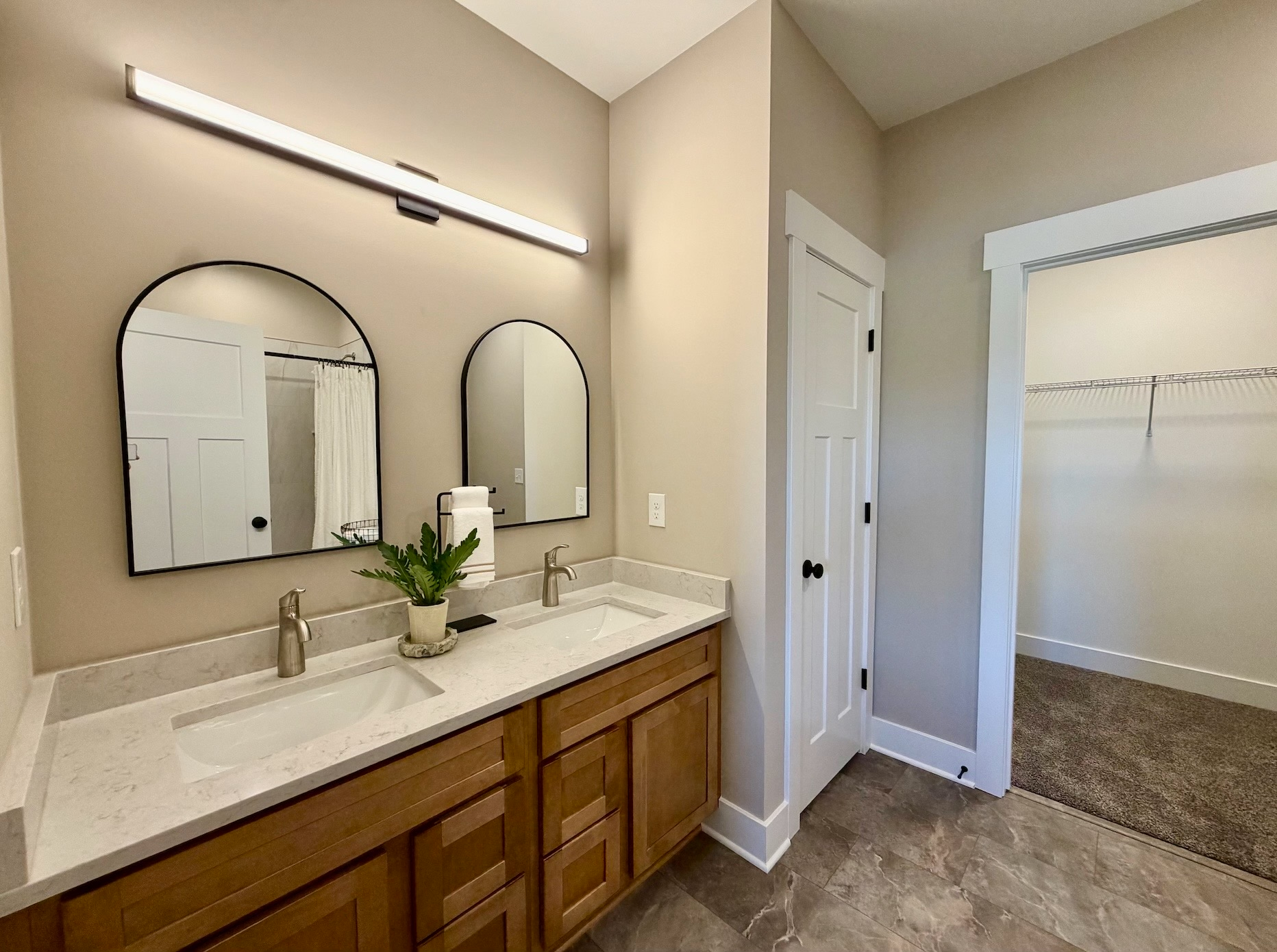 Staged primary bathroom with double vanity, arched mirrors, and decorative touches