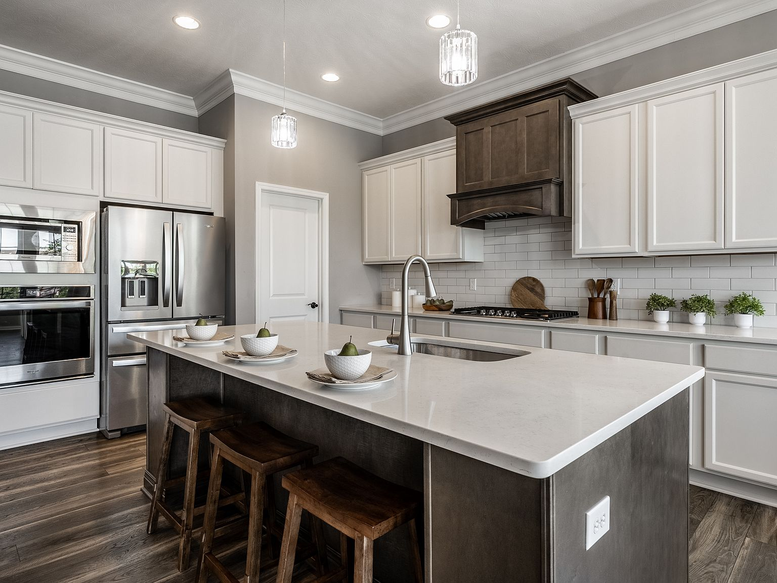 Gourmet kitchen with white and dark cabinetry, quartz countertops, and pendant lighting