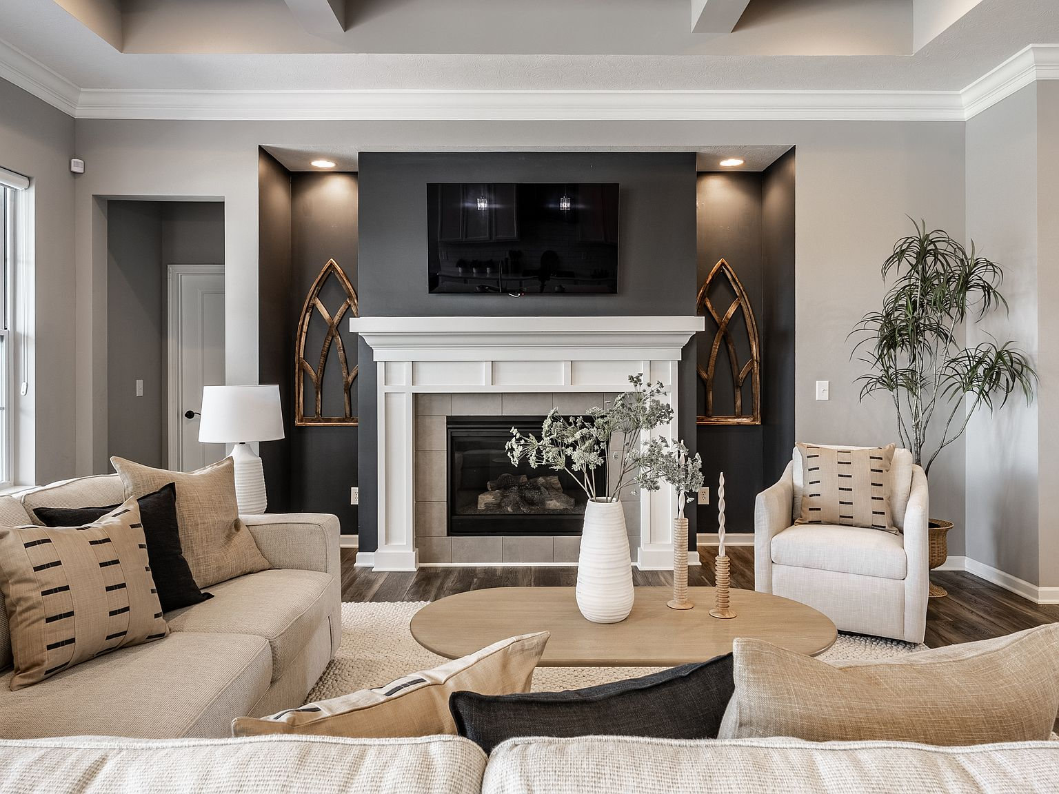 Living room with fireplace, white crown molding, tray ceiling, and dark accent wall