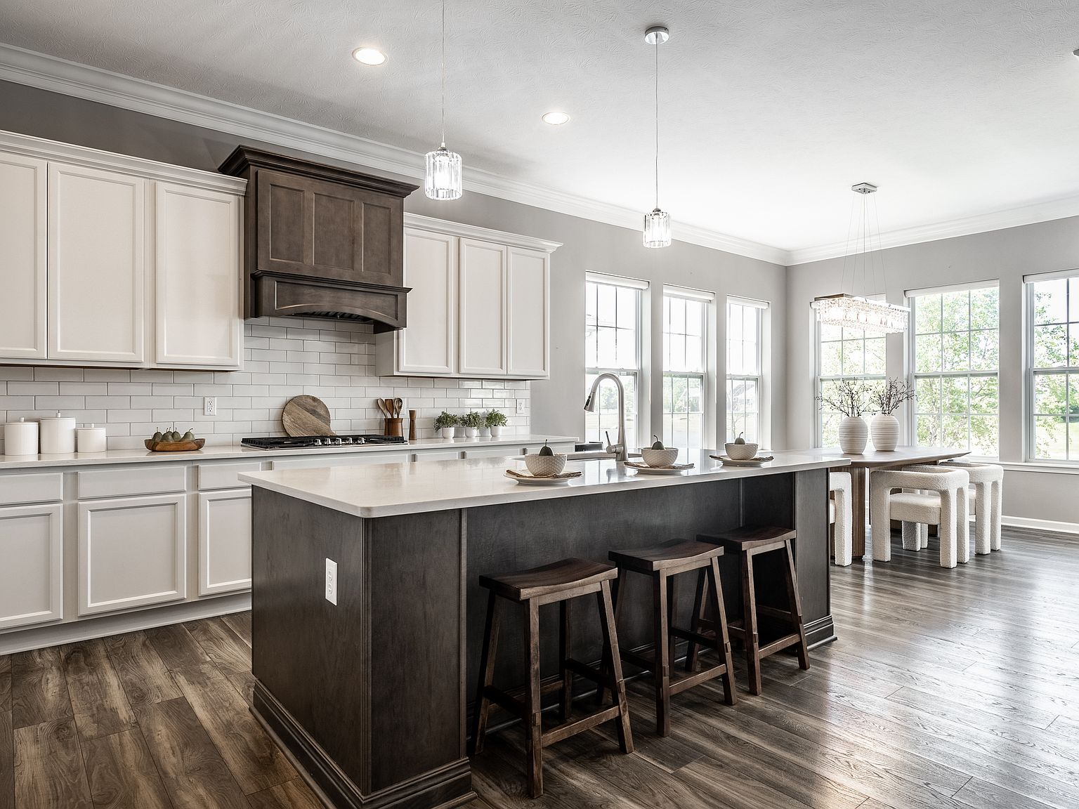 Gourmet kitchen with two-tone cabinetry, quartz countertops, crystal chandelier, and expansive windows