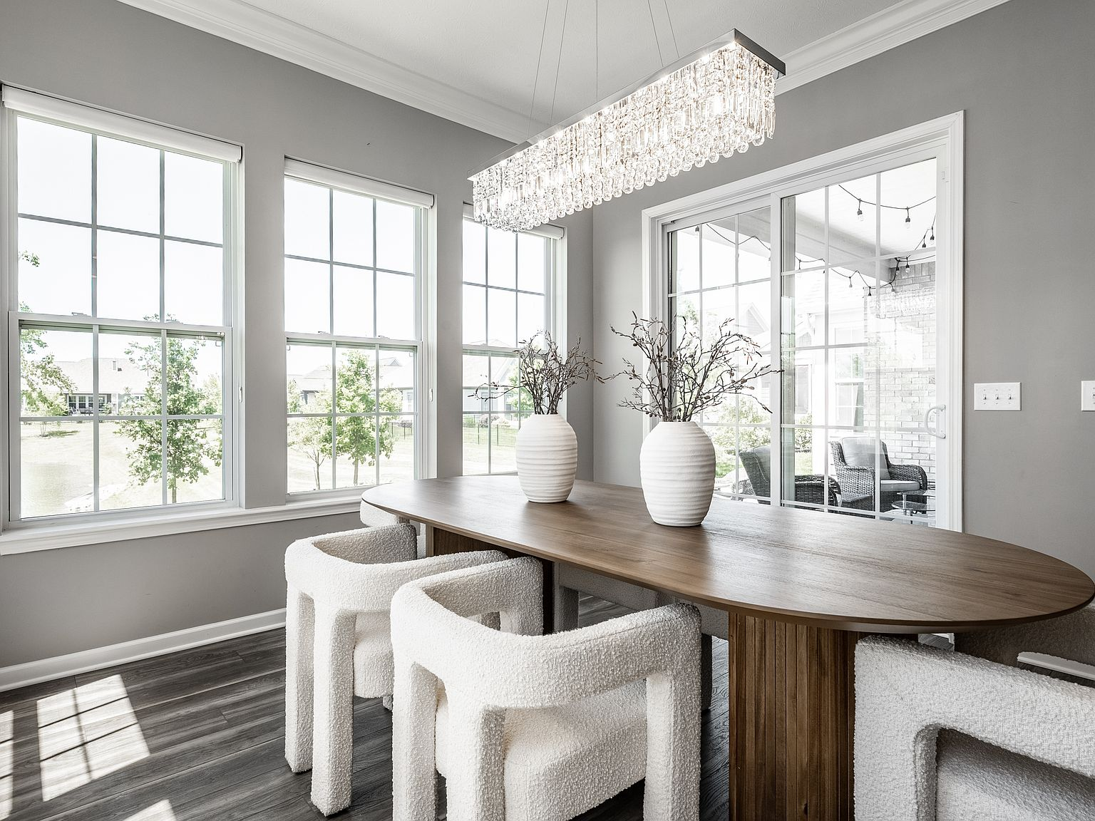 Dining room with oval table, upholstered chairs, and sliding glass door with pond views