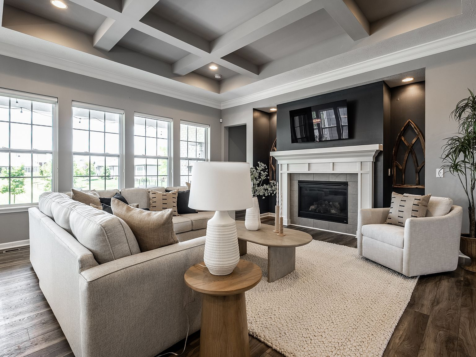 Living room with coffered ceiling, dark accent wall, tile fireplace surround, and wood floors