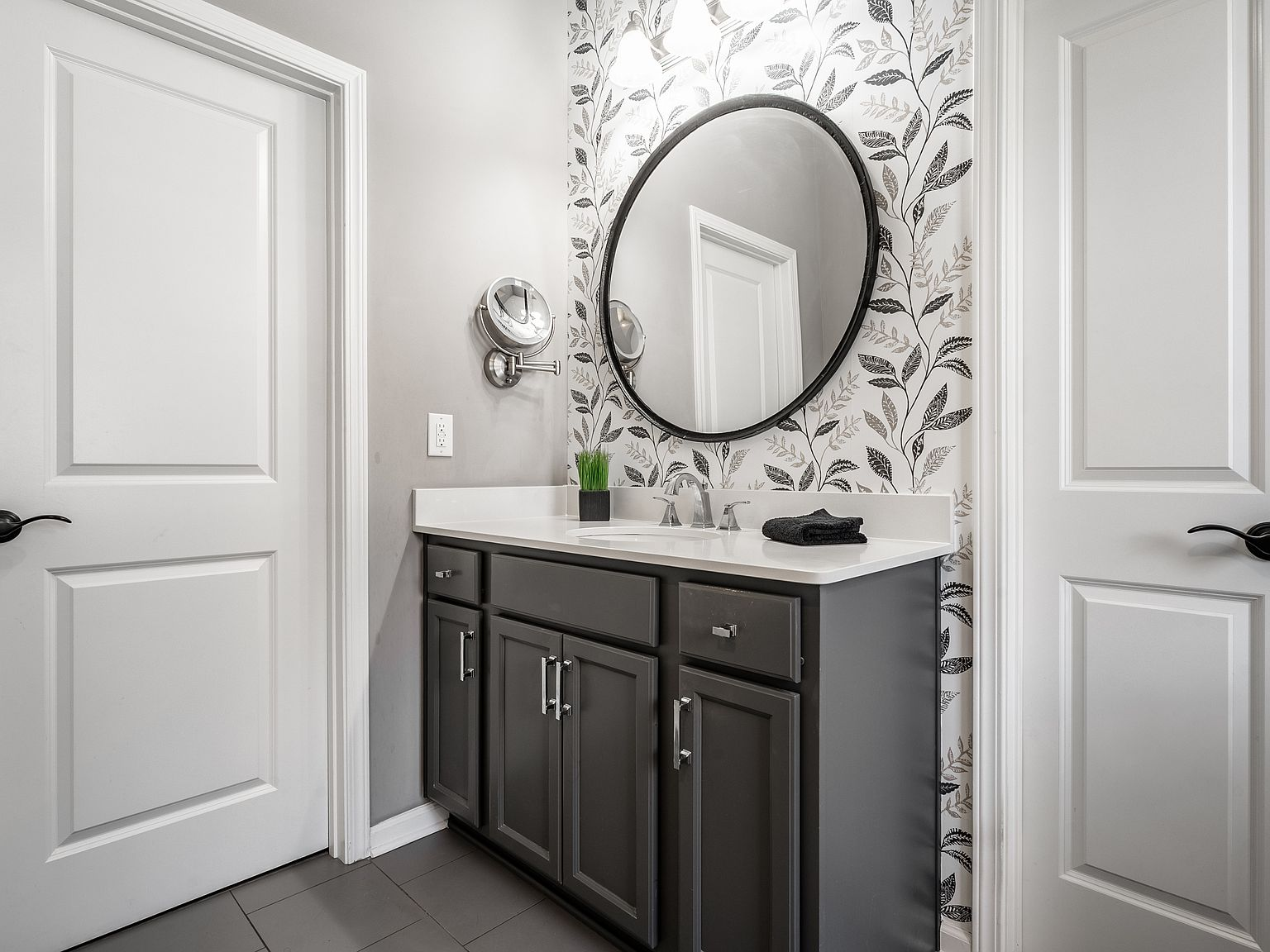 Renovated bathroom with dark vanity, quartz countertop, and botanical wallpaper