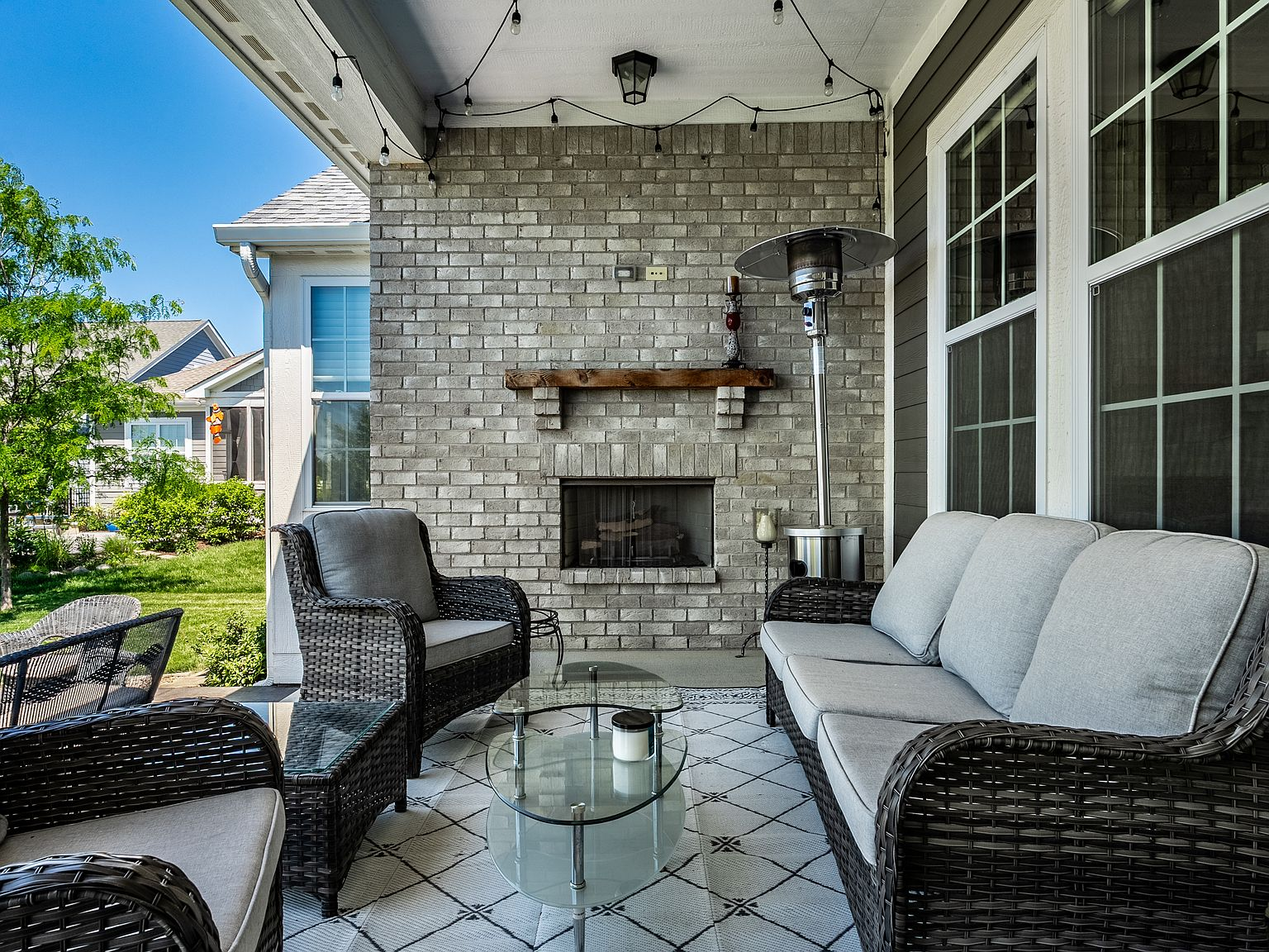 Covered backyard patio with brick fireplace and wicker furniture set