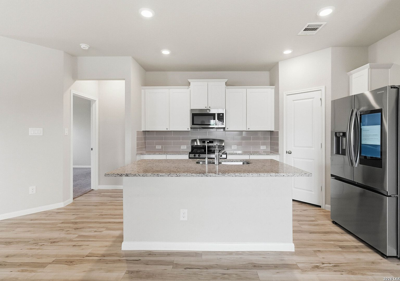Modern kitchen with white shaker cabinetry, granite countertops, and Samsung smart refrigerator