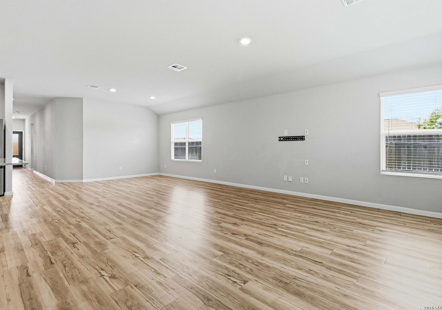 Open-concept living room with luxury vinyl plank flooring and recessed lighting