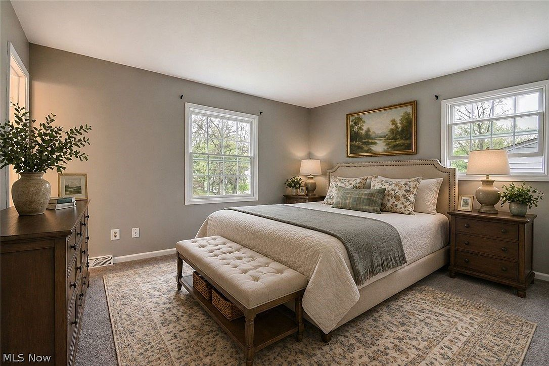 Master bedroom with neutral tones, dark wood furniture, and natural daylight