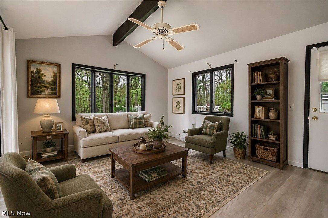 Living room with vaulted ceiling, dark wood faux beams, and light wood plank flooring