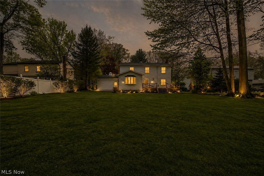 Rear exterior at twilight with landscape lighting and expansive lawn