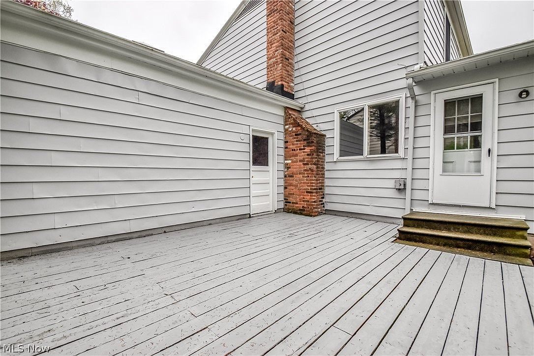 Wood deck with red brick chimney and gray siding exterior