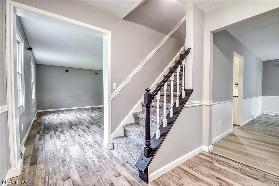 Foyer with wainscoting, luxury vinyl plank flooring, and carpeted stairs