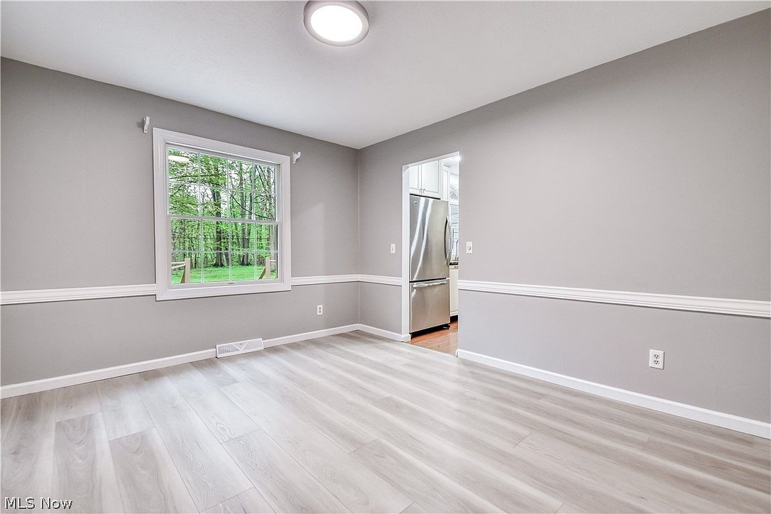 Dining room with grey walls, white chair rail molding, and light wood-look flooring