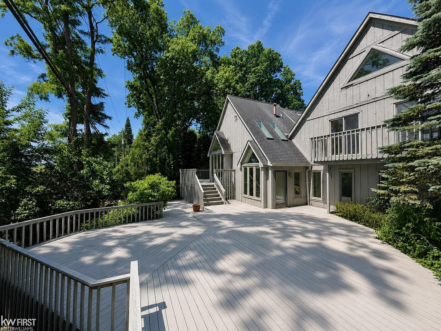 Multi-level wood deck at the rear of the home surrounded by trees