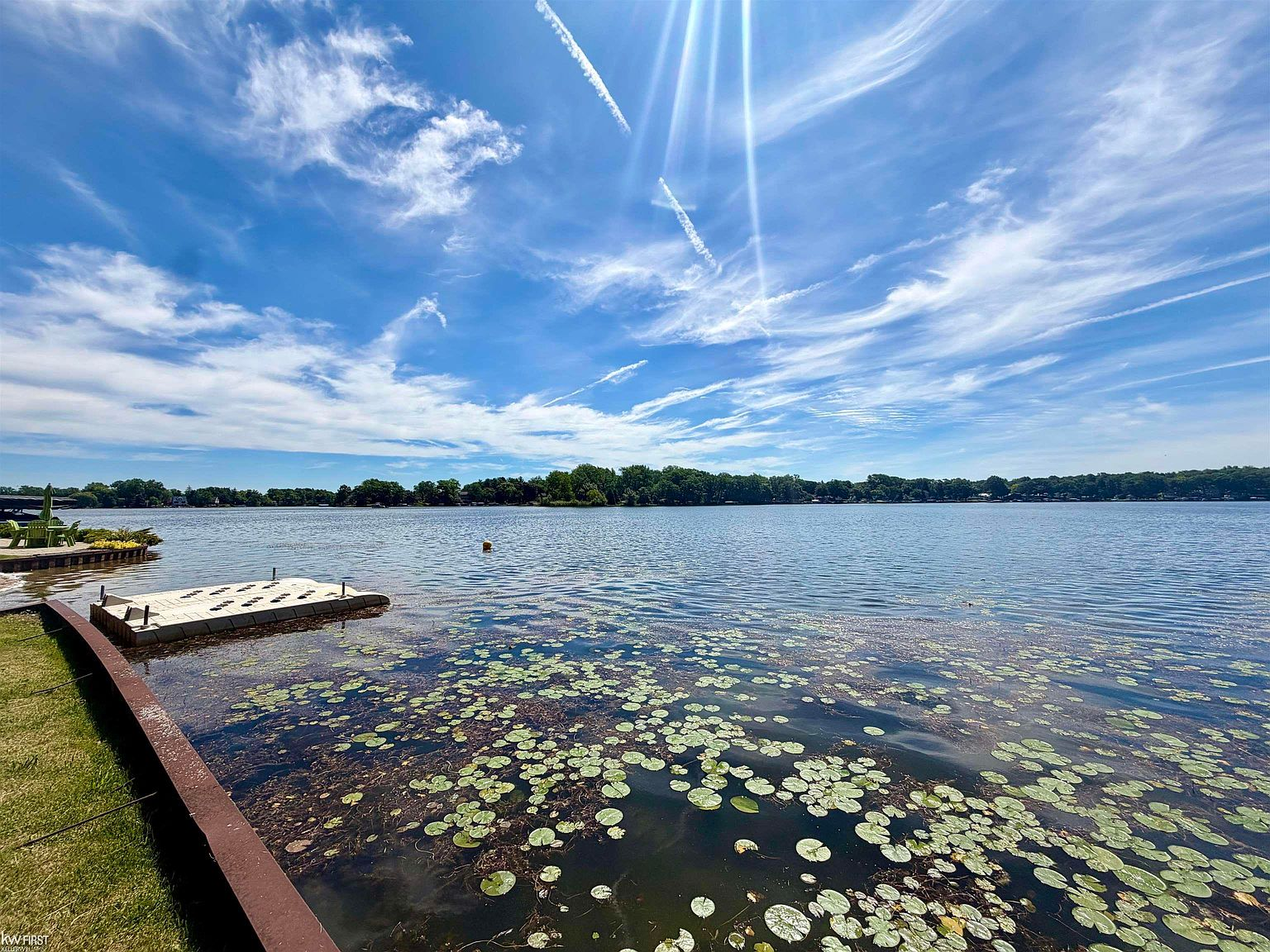 Big Lake waterfront view with lawn, retaining wall, and swimming dock in Davisburg, Michigan