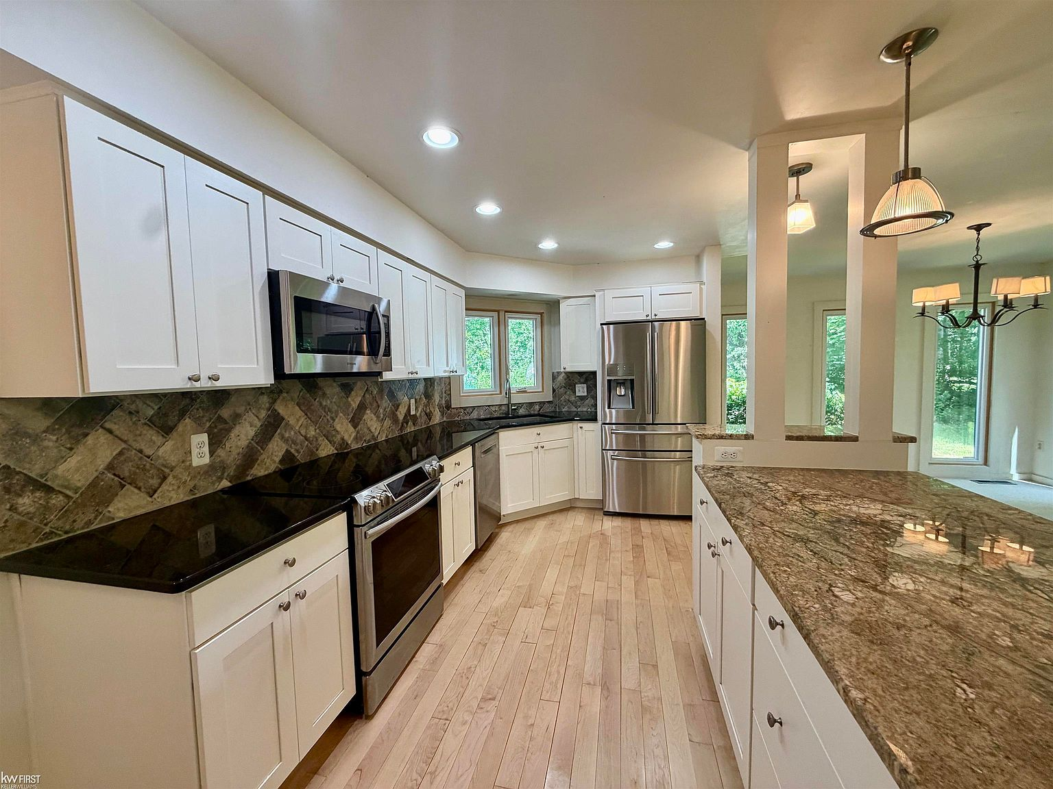Renovated kitchen with white cabinetry, granite countertops, and stainless steel appliances