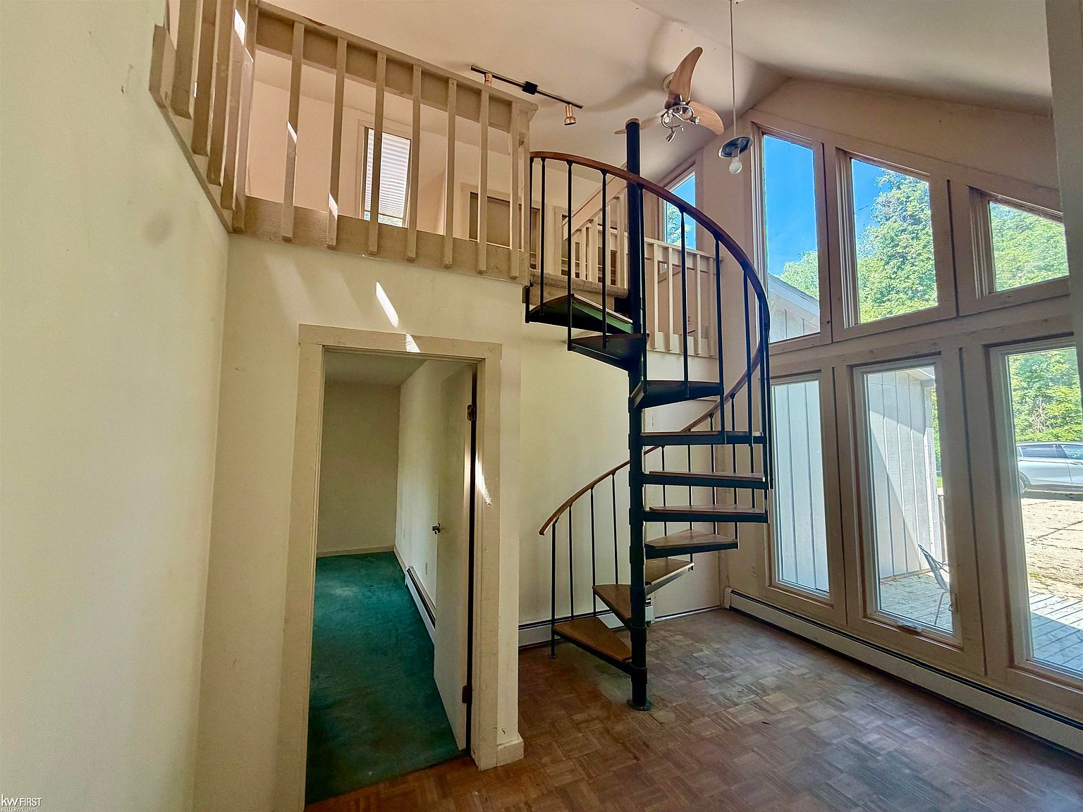 Living room featuring a dramatic spiral staircase and vaulted ceilings