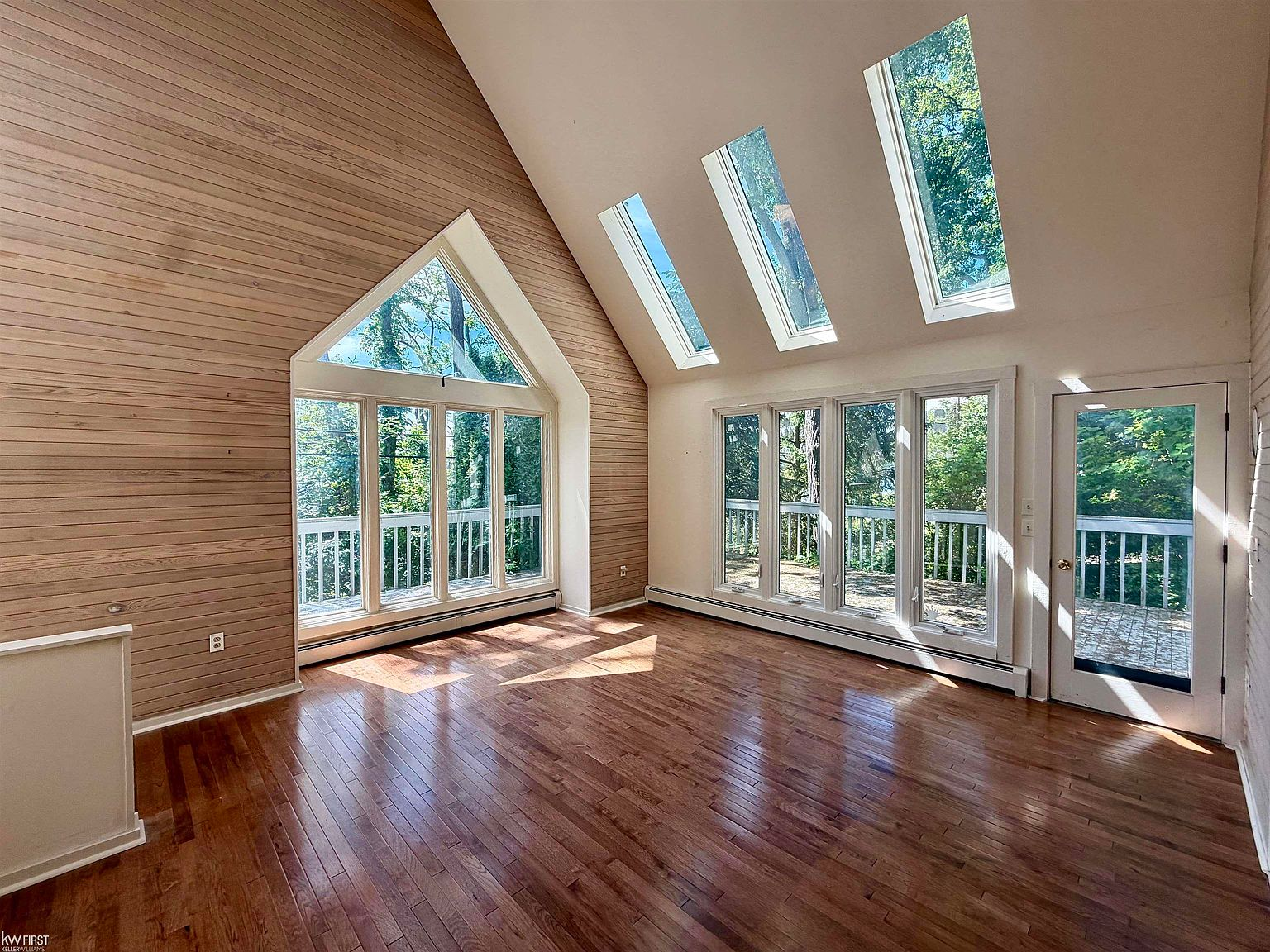 Vaulted living room with wood plank paneling and floor-to-ceiling windows