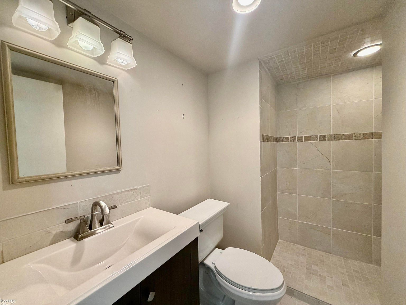 Remodeled bathroom with dark wood vanity and subway tile shower