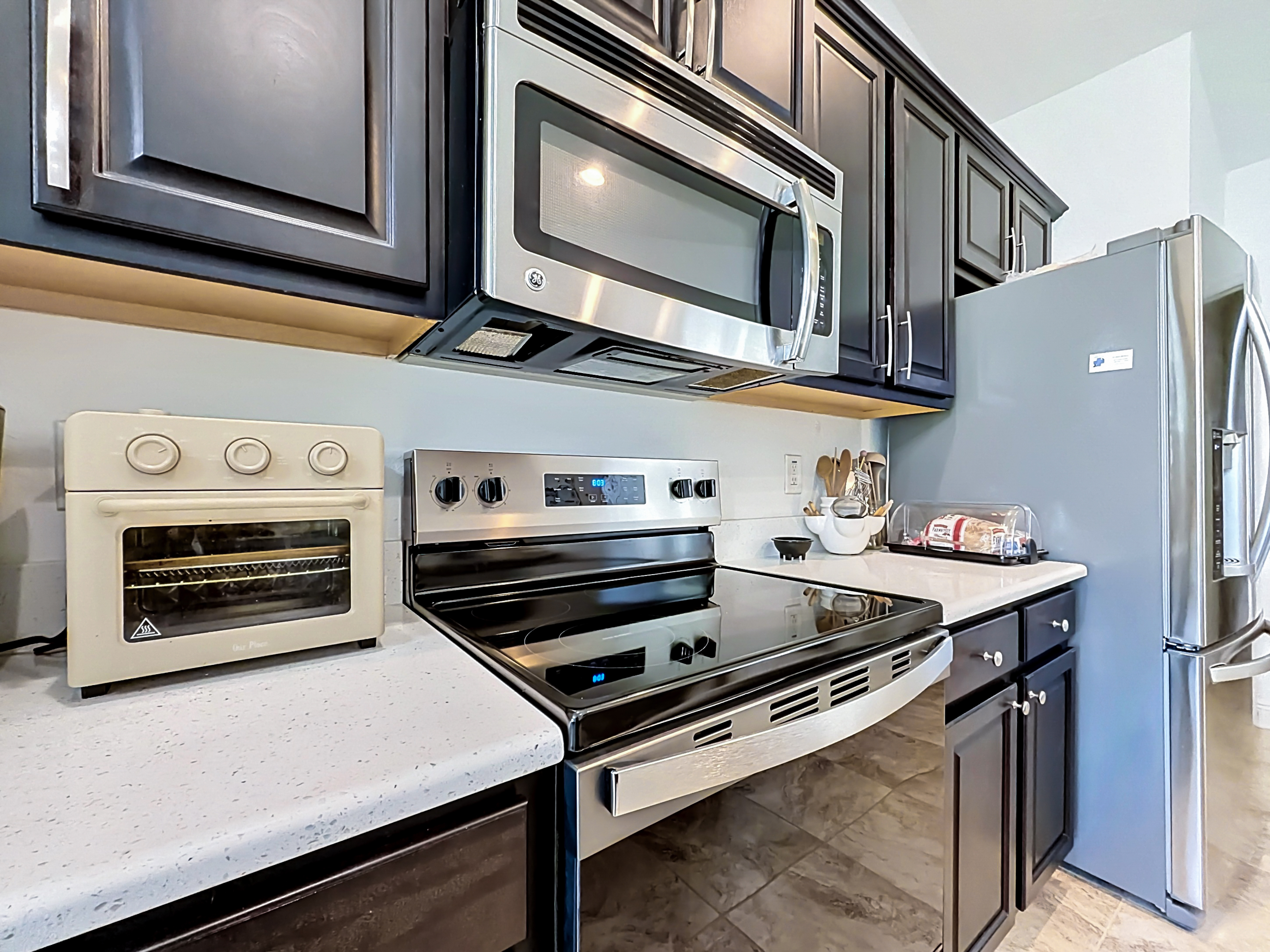 Modern kitchen with dark espresso shaker cabinets, white quartz countertops, and stainless steel appliances
