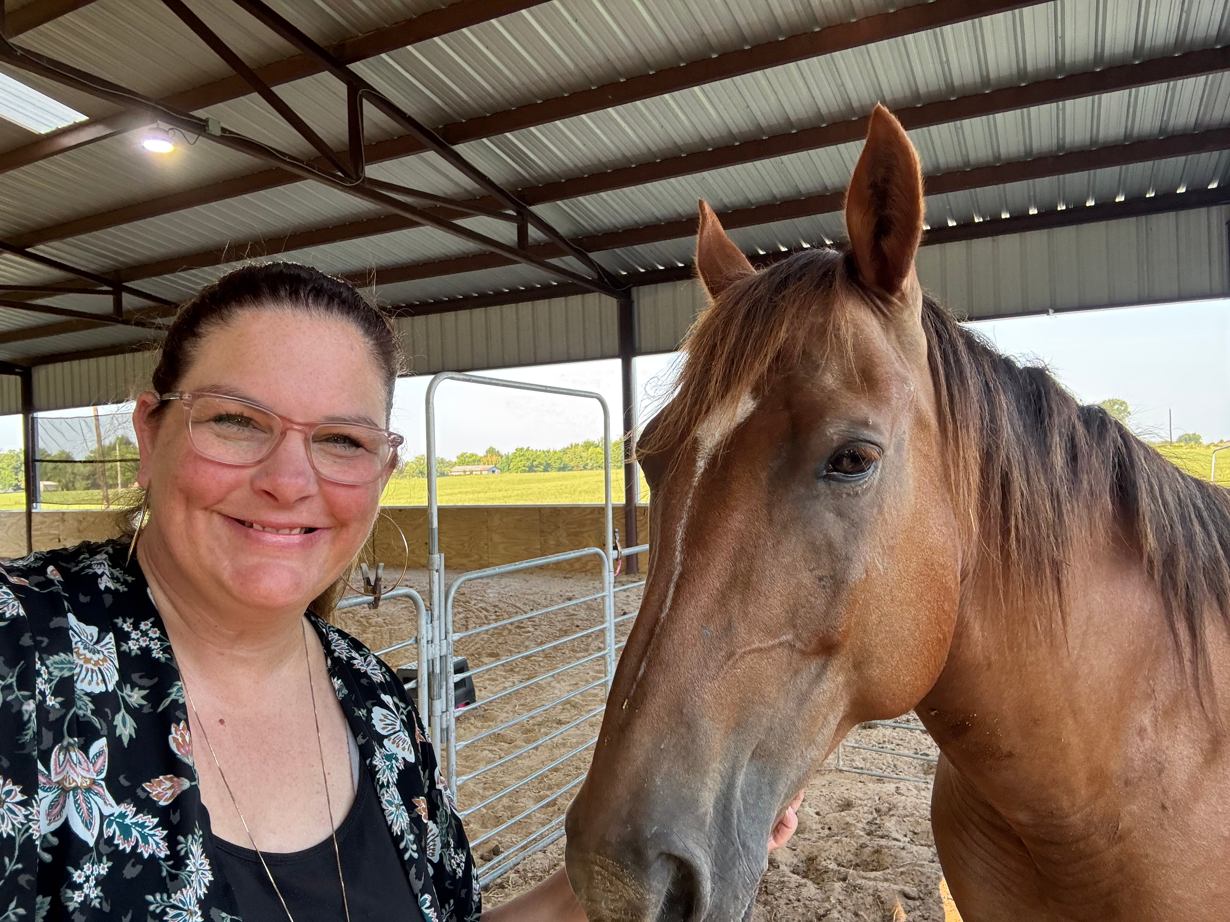 Shannon Miles with a brown horse in a covered equestrian arena, supporting the Tailored Rides community organization