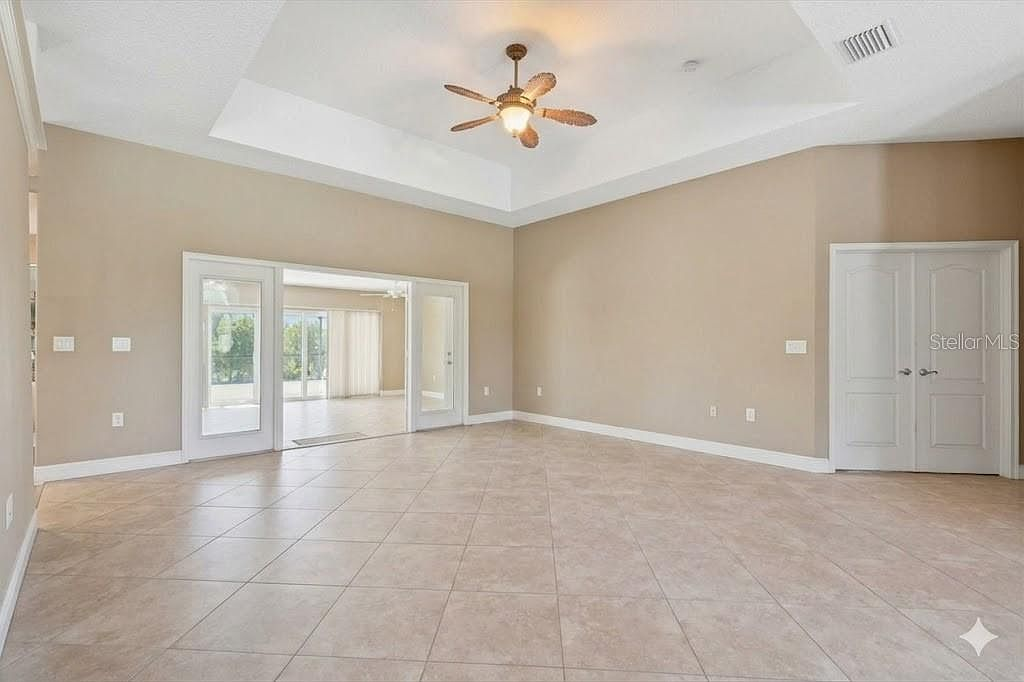 Open living room with tray ceilings and ceramic tile flooring