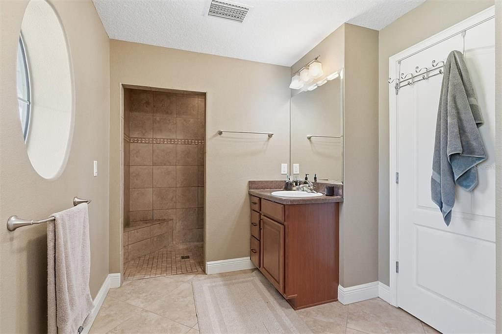 Bathroom with tiled walk-in shower and wood vanity