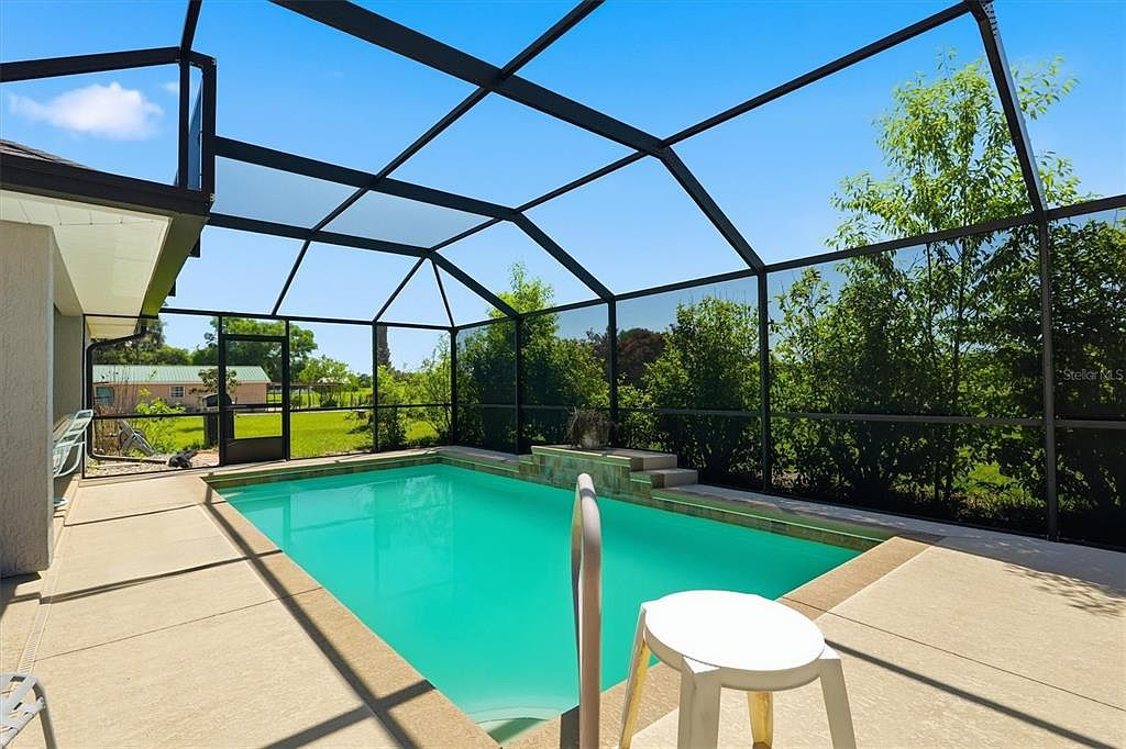 Screened-in swimming pool with water feature and concrete deck