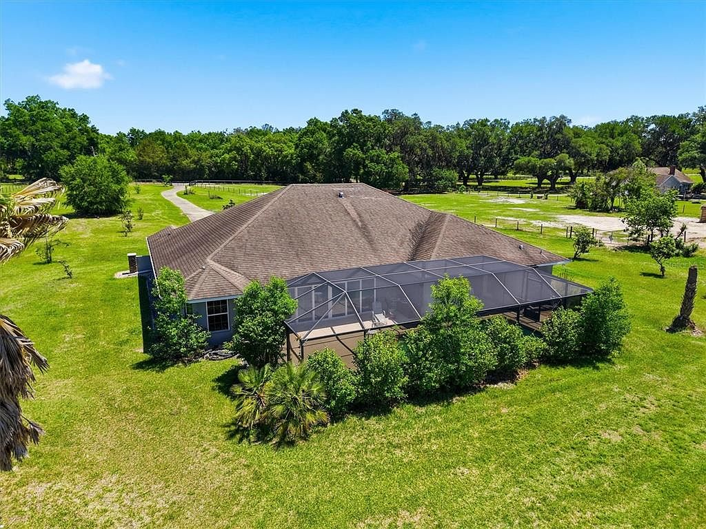 Drone shot of rear exterior showing pool enclosure and pasture