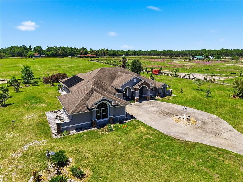 Aerial view of ranch property with circular driveway and pasture