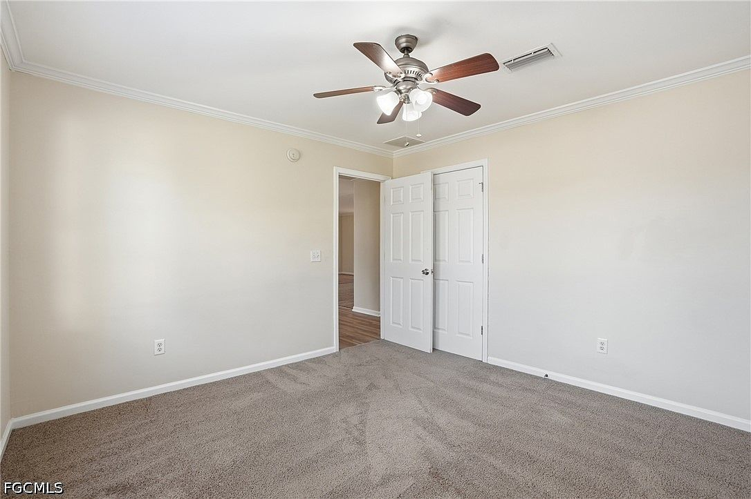 Primary bedroom with neutral walls and crown molding