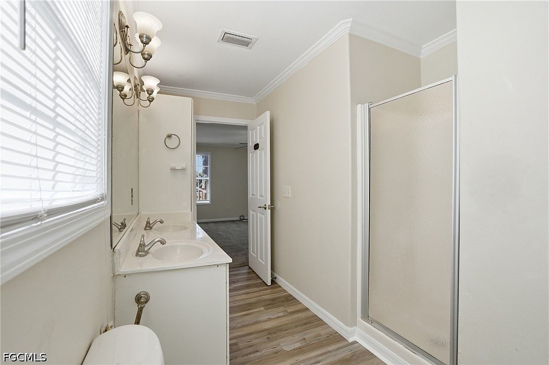 Bathroom with white vanity, brushed nickel hardware, and glass-door shower