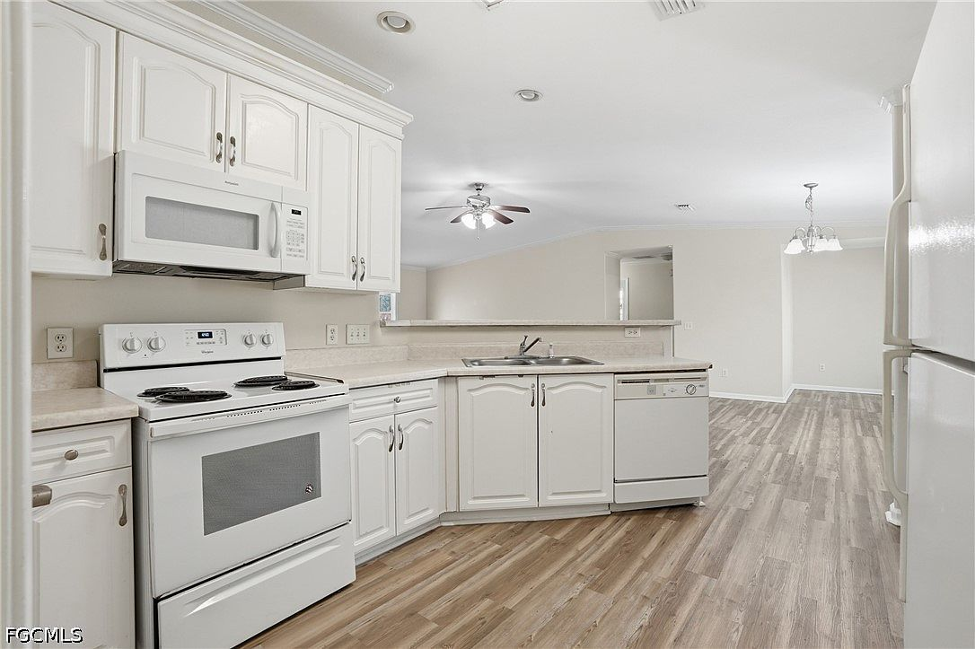 Kitchen looking toward dining area with white cabinets and natural light