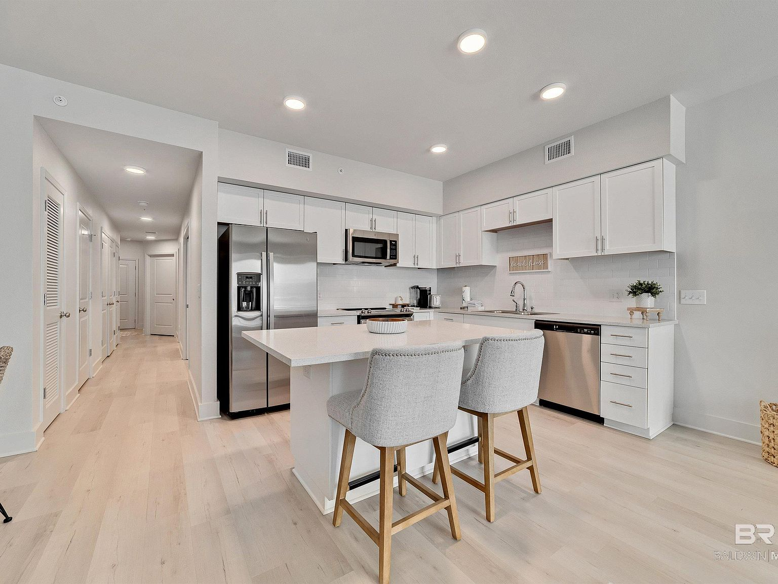Modern white kitchen with quartz countertops and stainless steel appliances