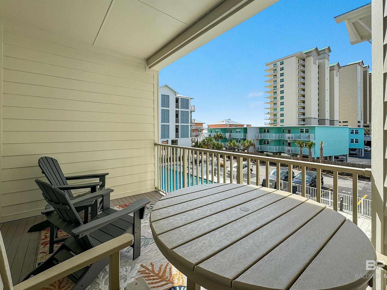 Covered private balcony with outdoor seating and pool view