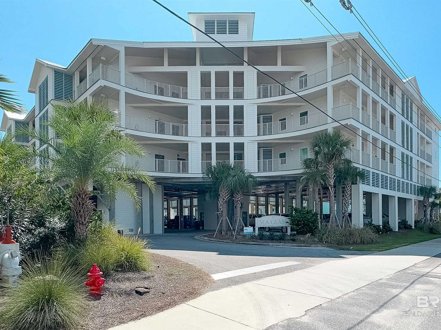 Sea Glass condo complex facade with palm trees and modern coastal architecture