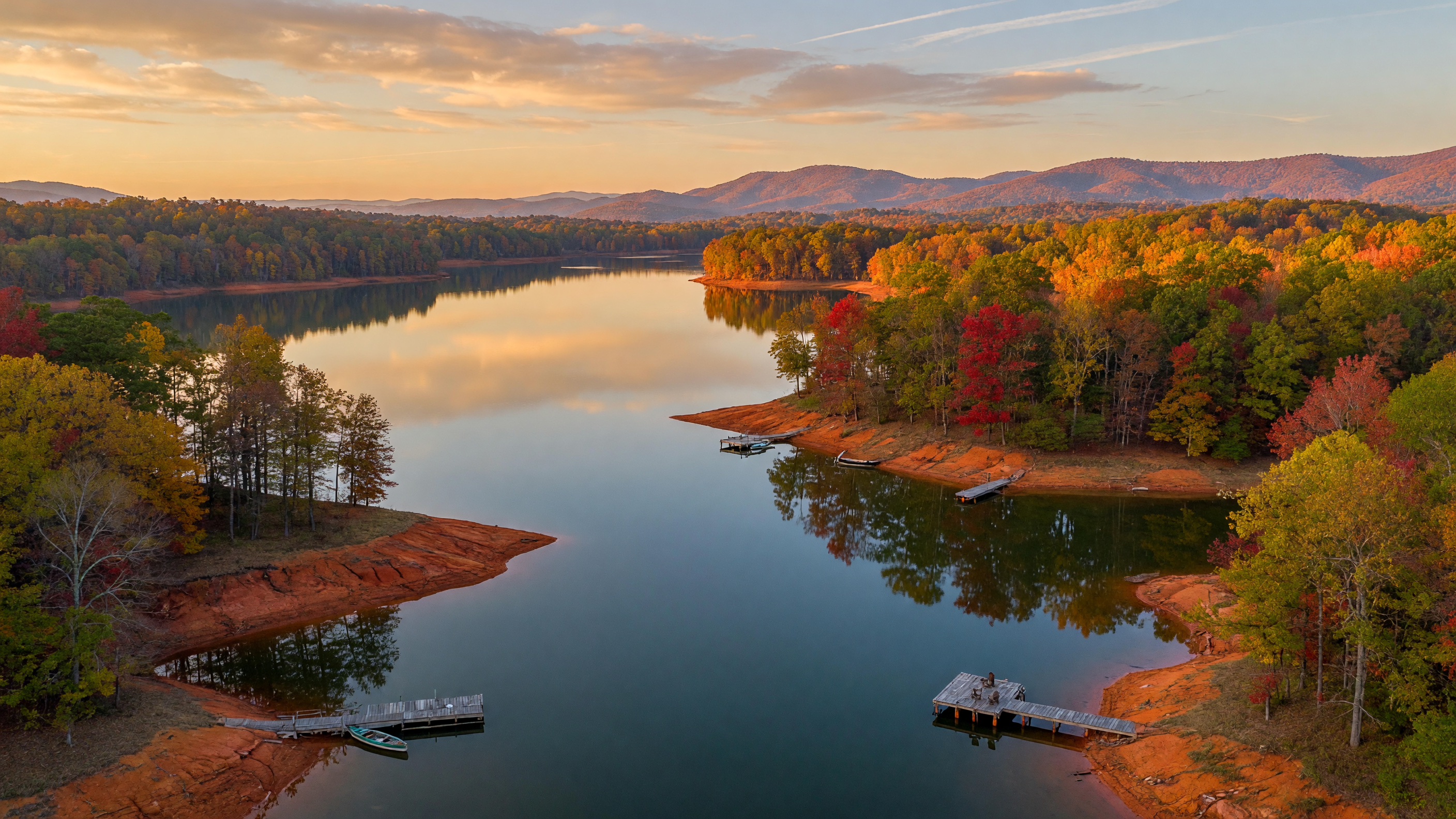 Aerial view of a serene Georgia lake at golden hour with calm water reflecting autumn-colored forests