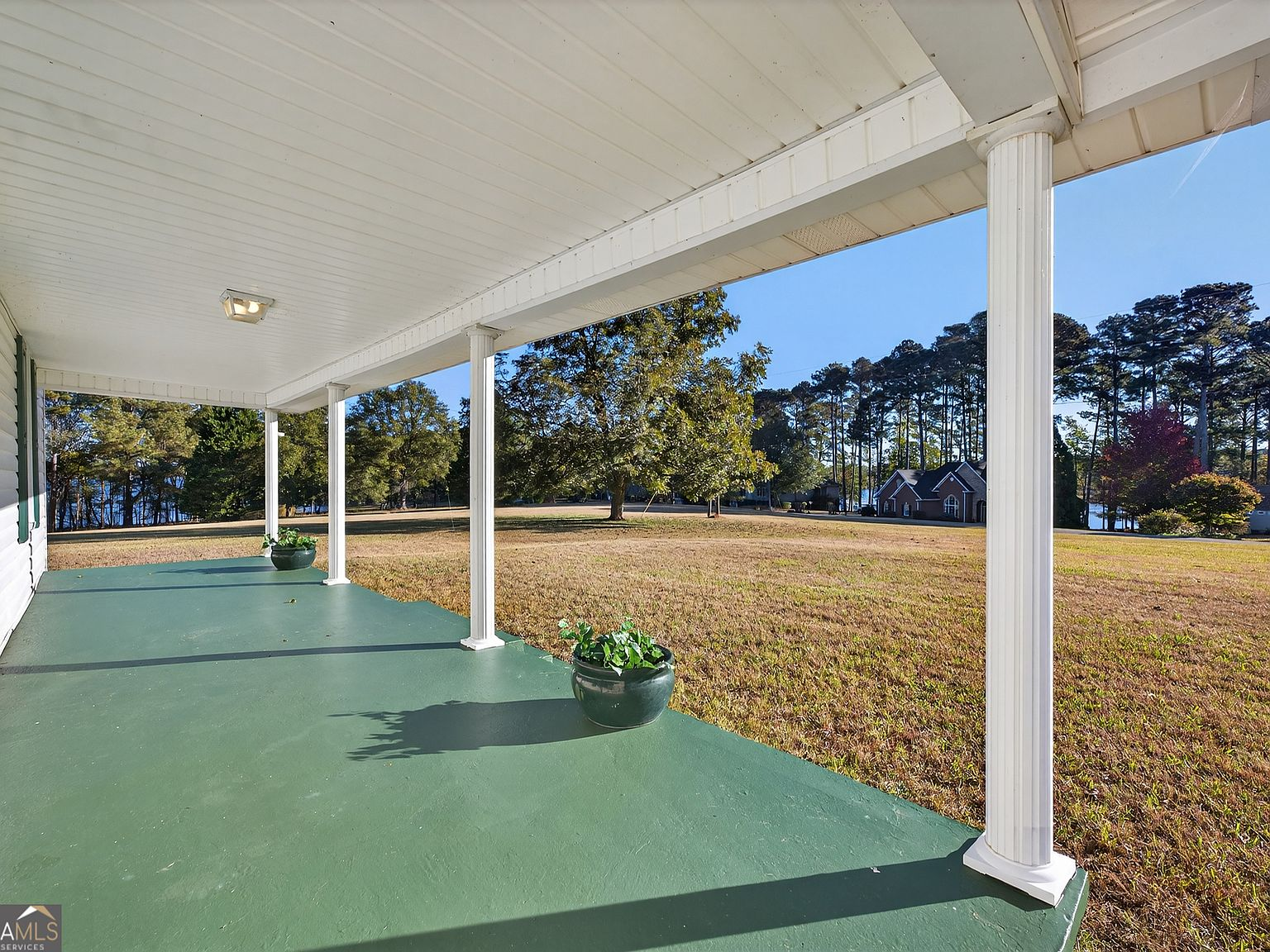 View from the covered porch with white columns looking across the lawn to the lake