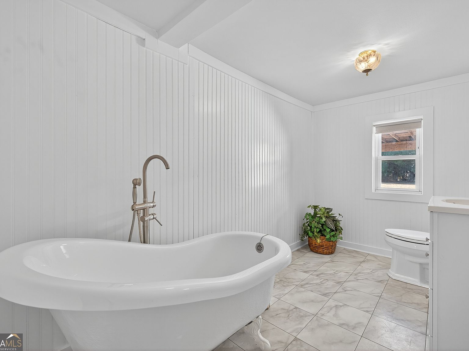 Historic bathroom with freestanding soaking tub and marble-style tile flooring