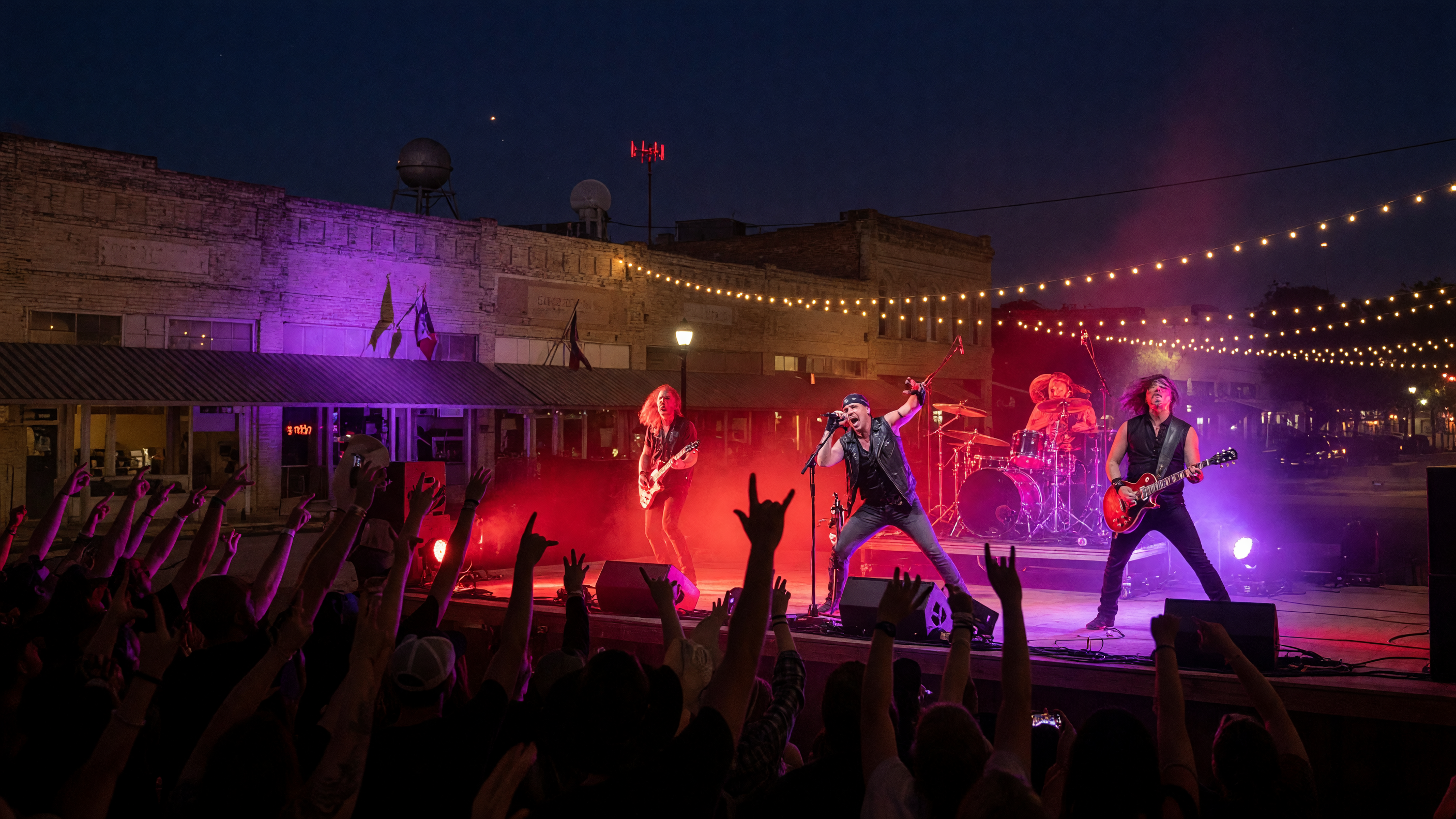 High-energy tribute band performing on an outdoor stage at night with vivid concert lighting