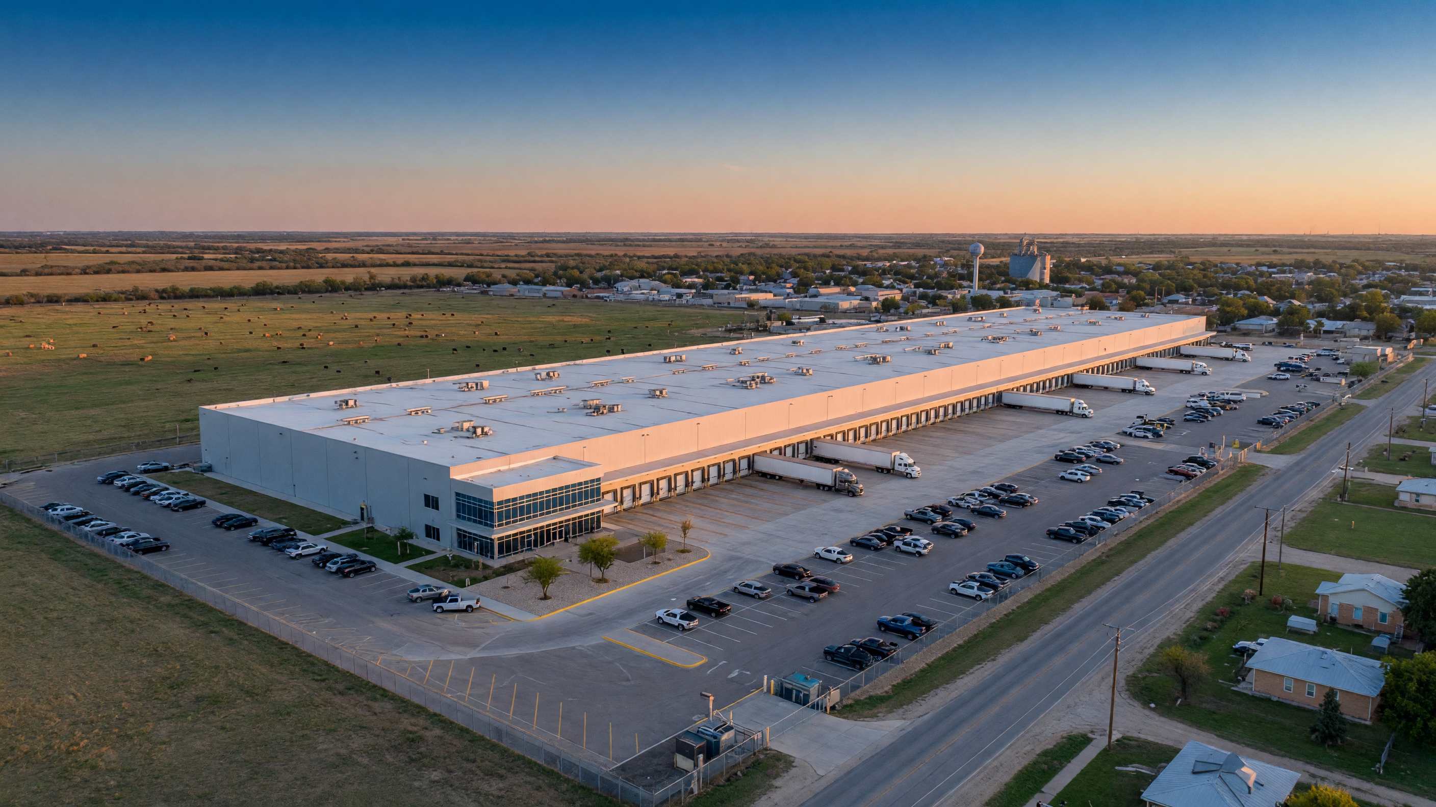 Large modern manufacturing facility expansion in a small Texas town with loading docks and green fields