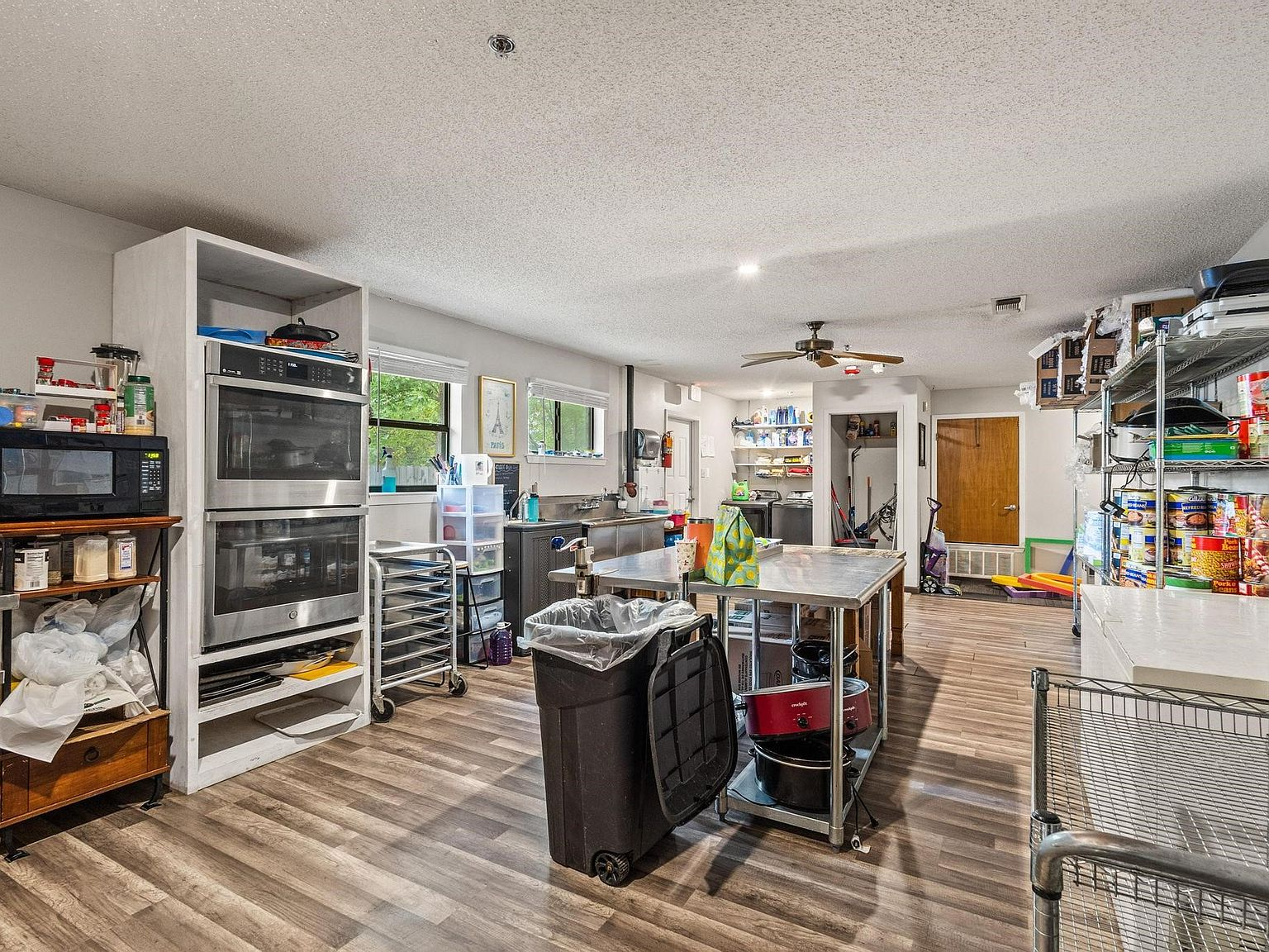 Wide-angle view of commercial kitchen with dual wall ovens and food prep island