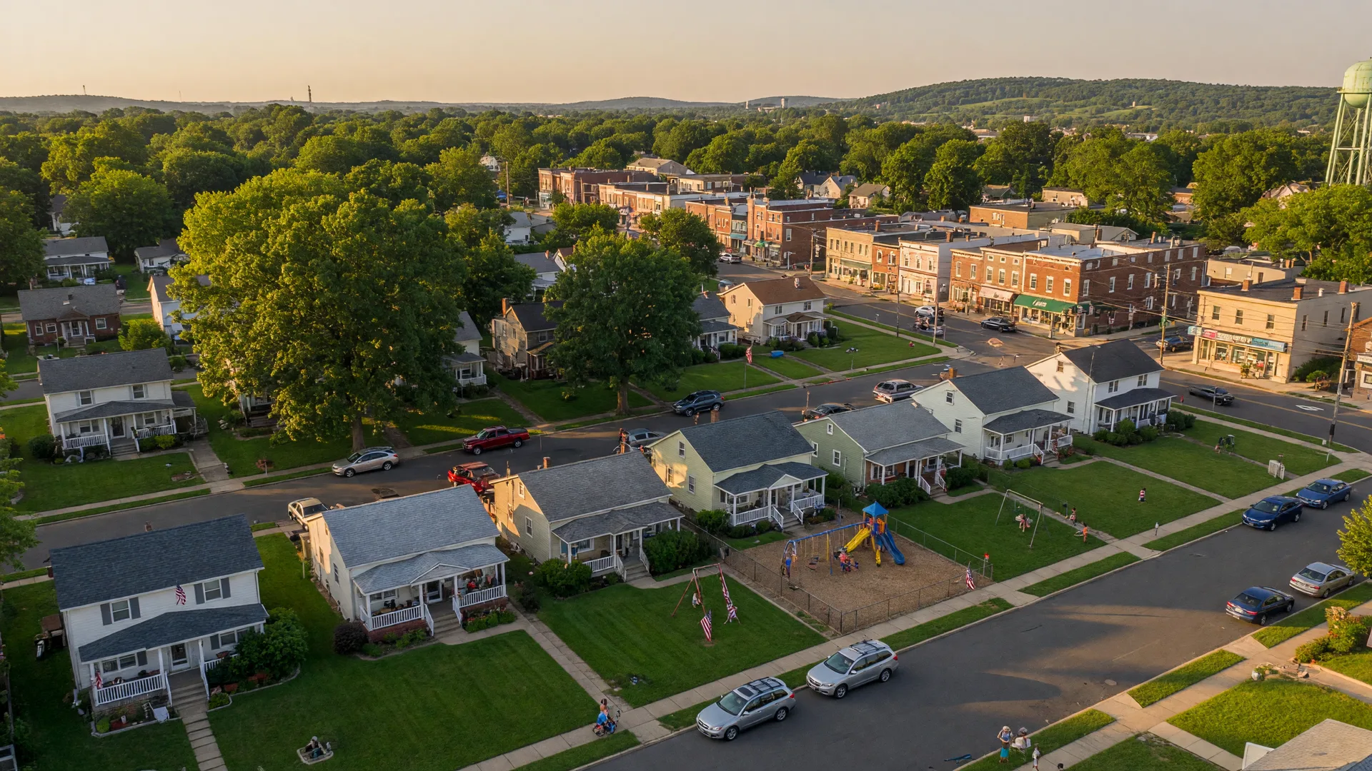 Aerial view of a charming North Jersey suburban neighborhood with tree-lined streets and mature trees at golden hour